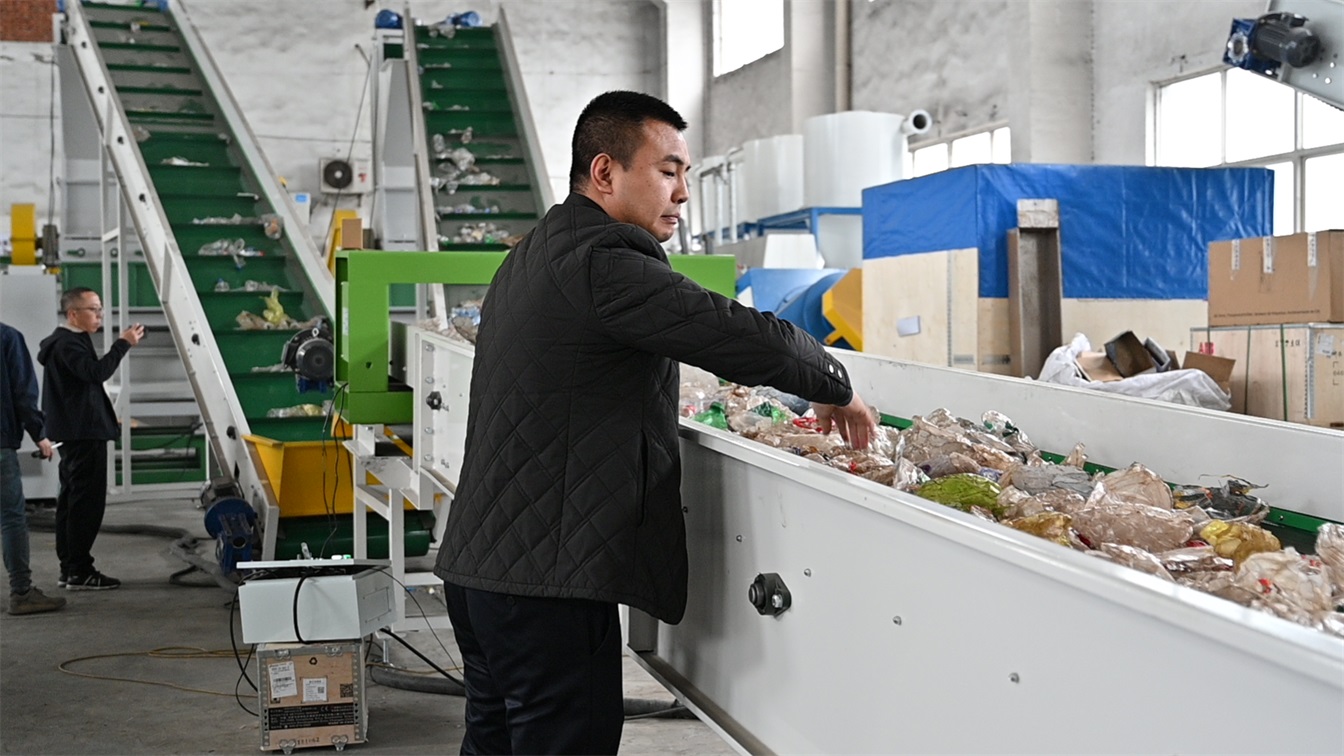 Sorting conveyor carrying mixed plastic film waste before it enters the washing line
