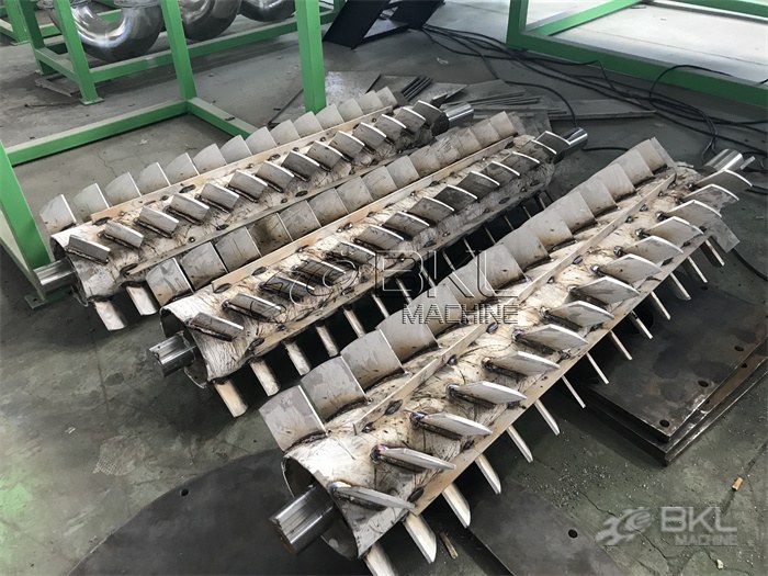 Three dryer rotor shafts with freshly welded stainless paddles laid out in the fabrication shop