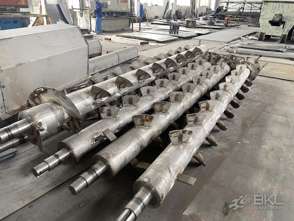 Three stainless friction washer rotor shafts with welded scoop paddles and machined bearing ends