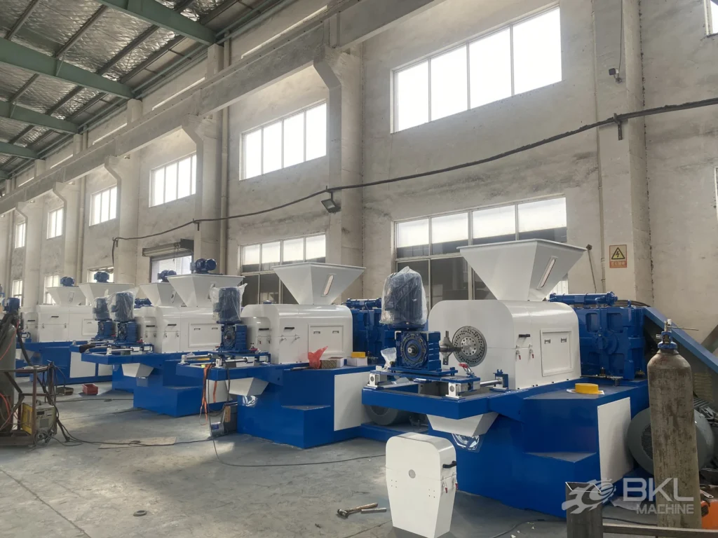 Squeezer units under assembly with the perforated die plate and blue gearbox exposed on the nearest machine