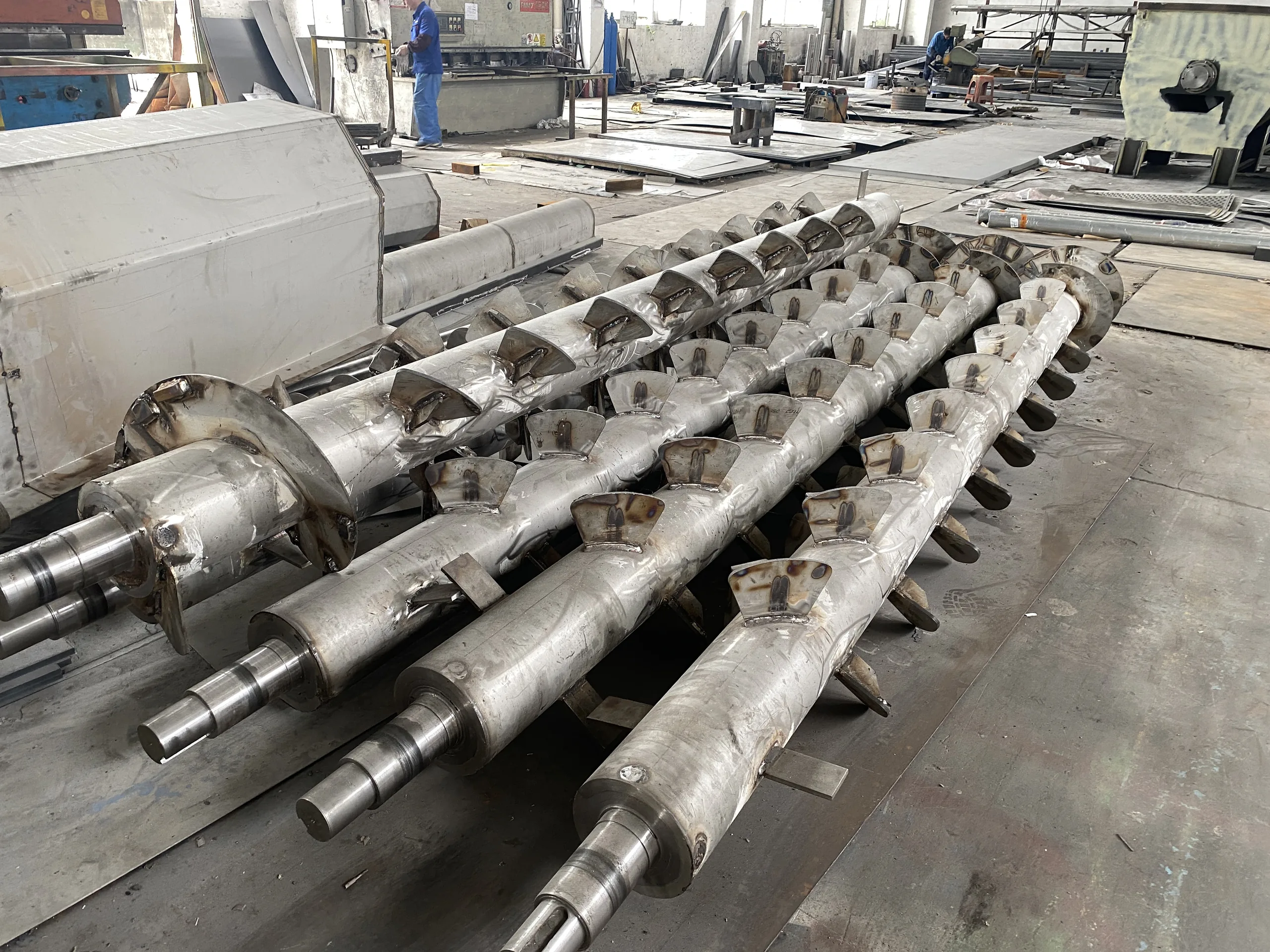 Three stainless friction washer rotor shafts with welded scoop paddles and machined bearing ends