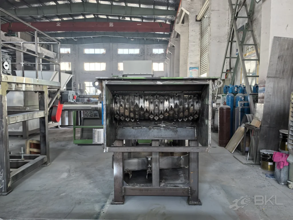 Bare steel shredder cutting chamber showing the bladed rotor and horizontal pusher plate during fabrication