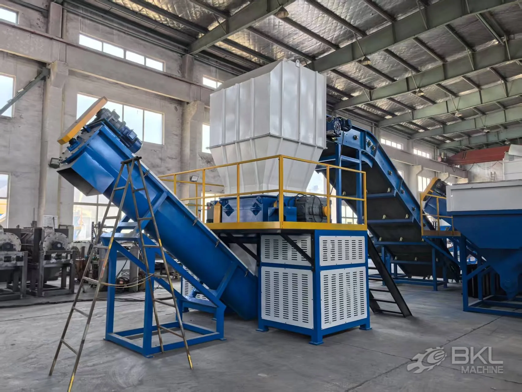 Twin-shaft shredder integrated in a recycling line with an infeed belt conveyor and inclined screw conveyor
