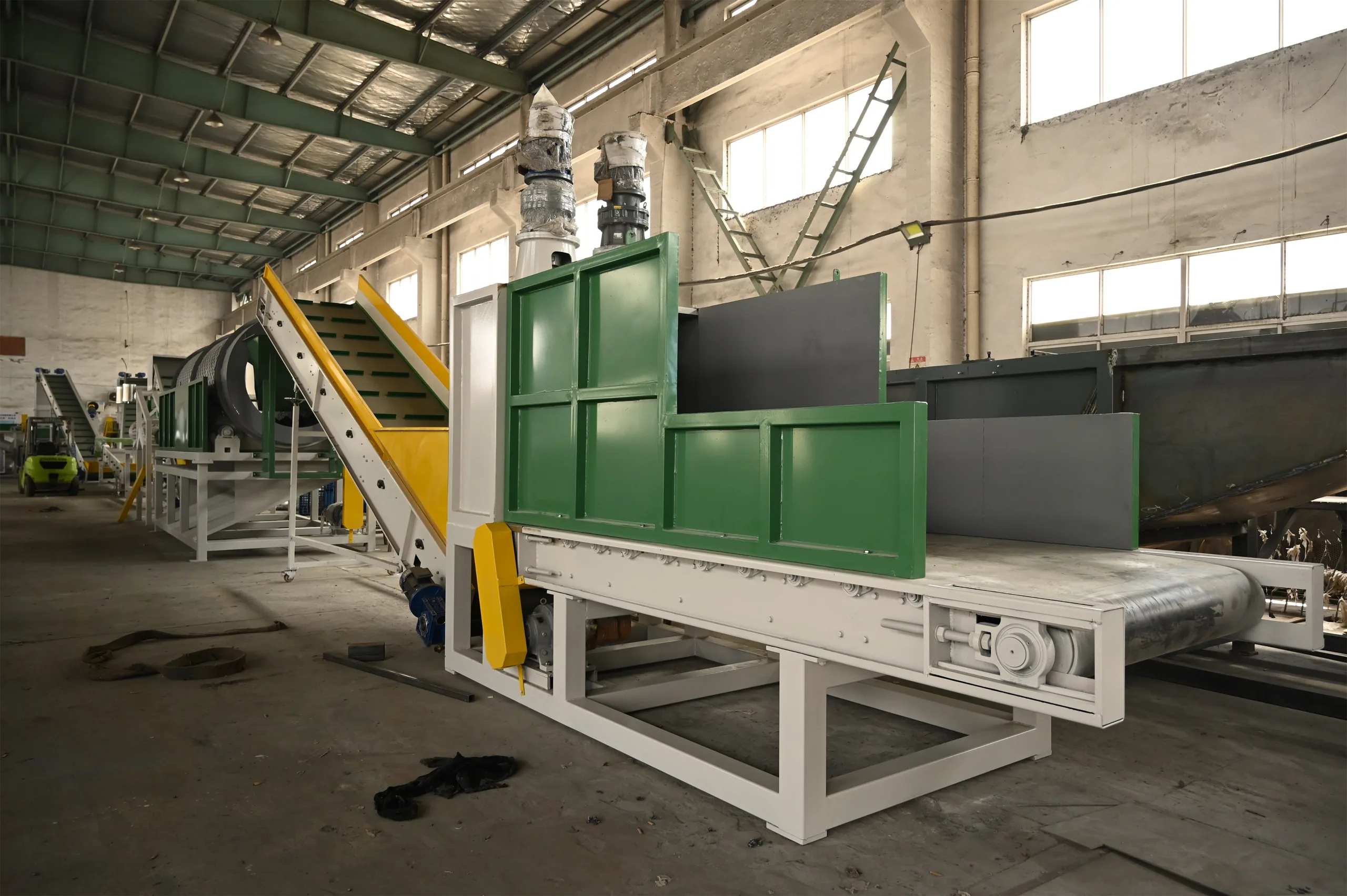 Belt feeder with green side walls loading bottles onto the trommel of a PET washing line
