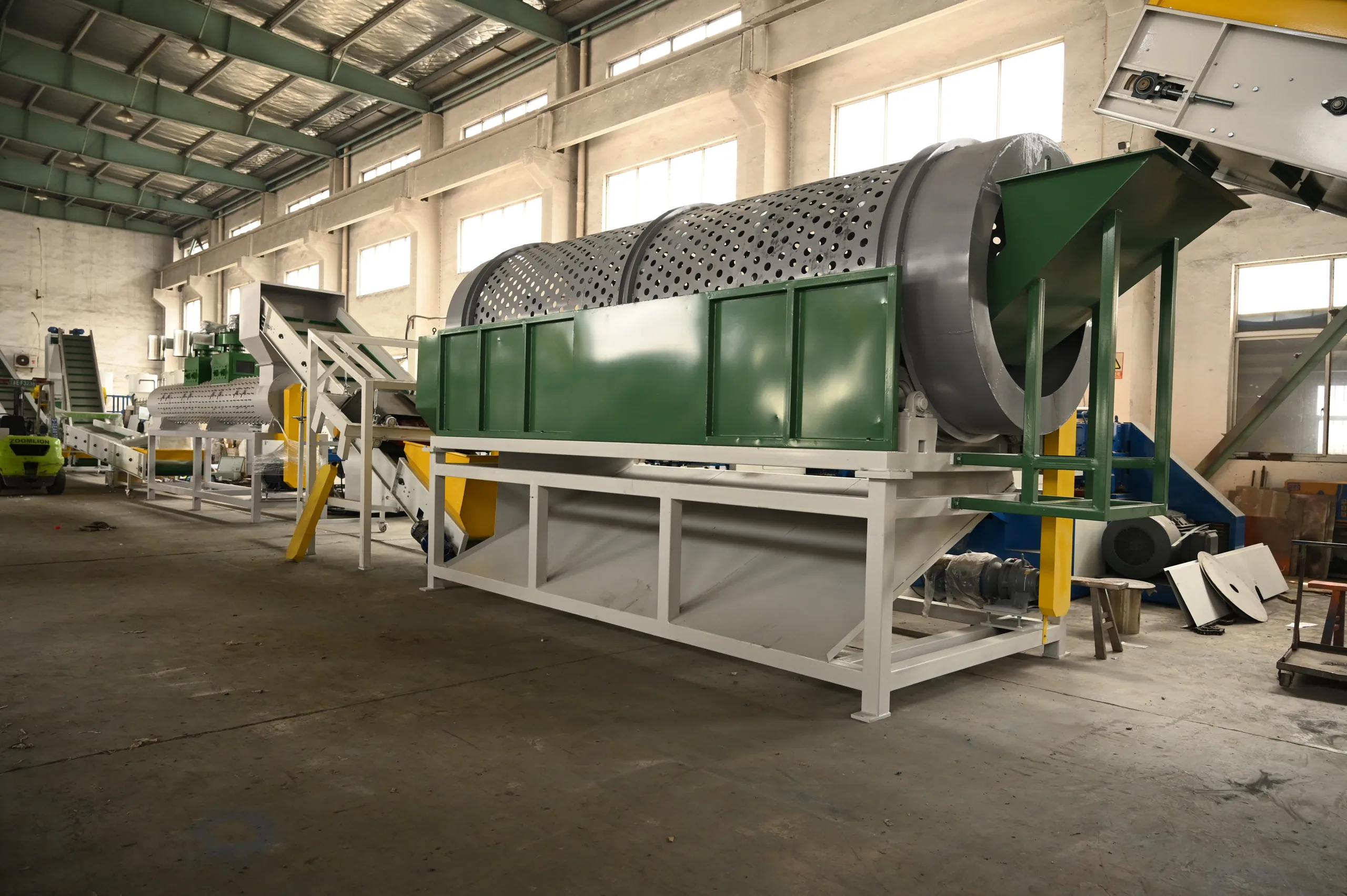 Perforated trommel drum screen removing sand and fines from PET bottles before washing