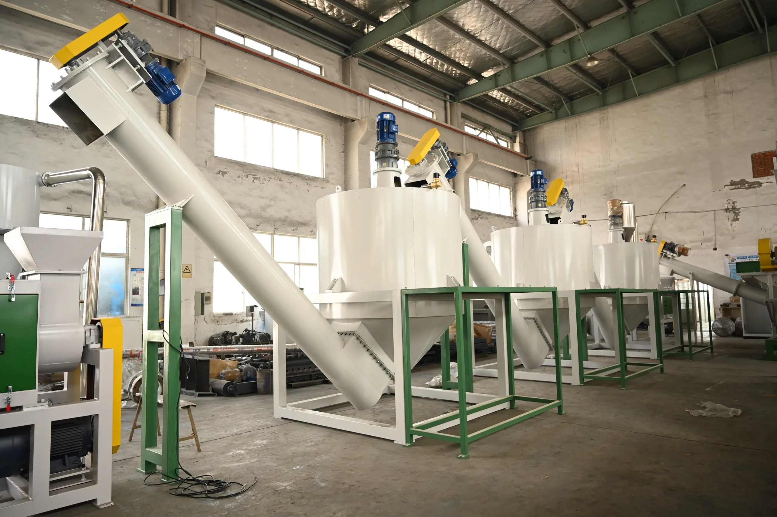 Three vertical hot wash tanks with top agitators fed by a steep screw conveyor