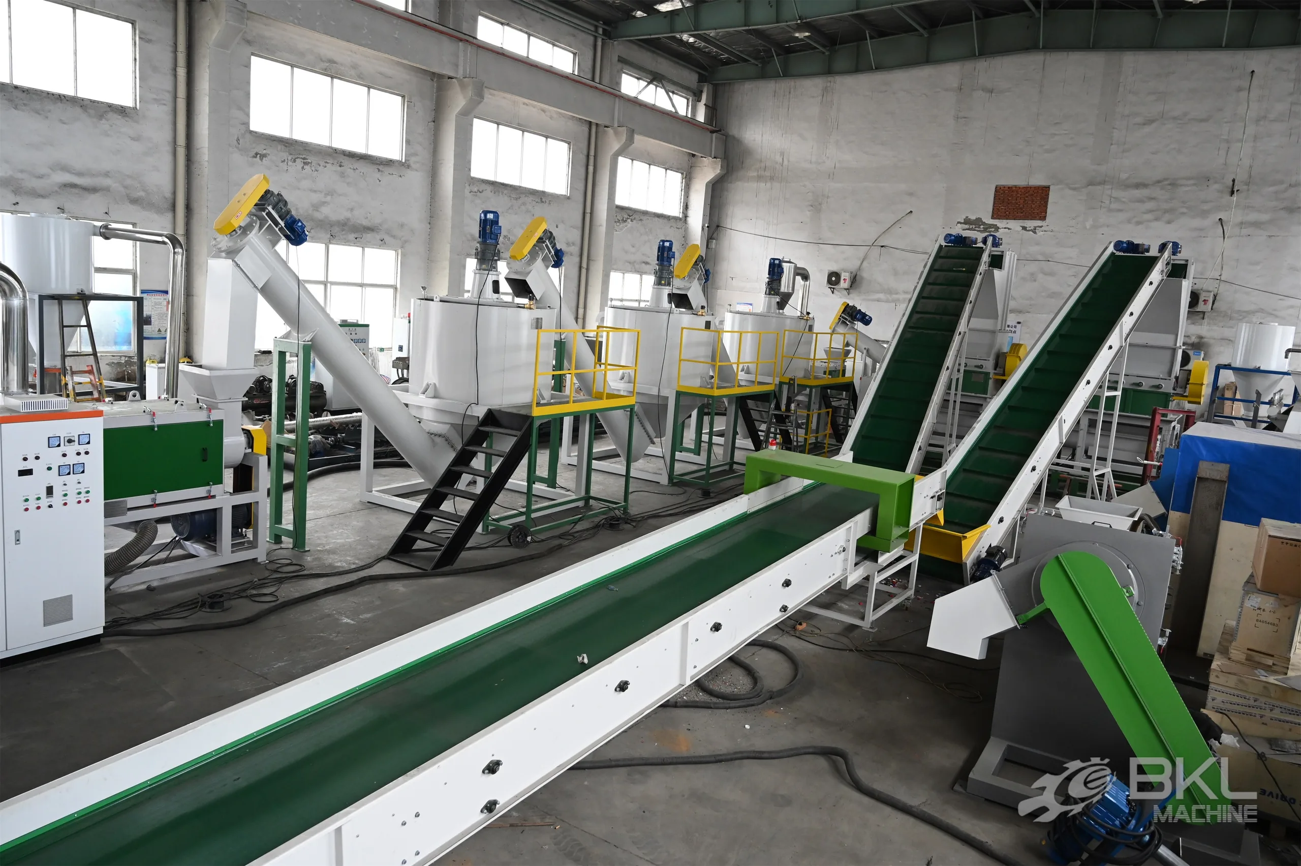 Hot wash tanks with agitator motors, access platforms and green belt conveyors in a PET washing line