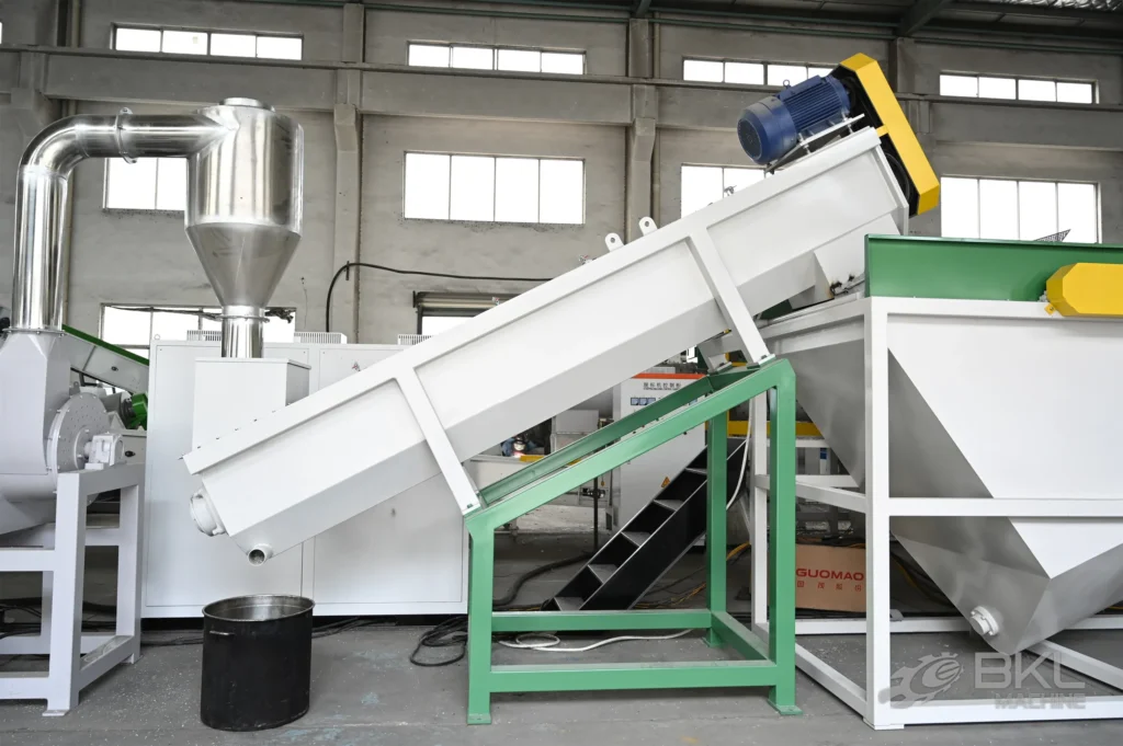 Inclined friction washer on a green support frame beside a cyclone and rinsing tank in a washing line