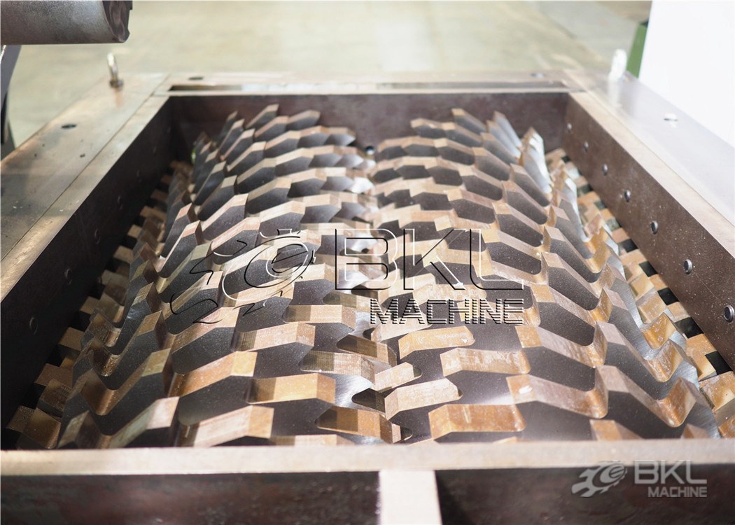 Top view into the twin-shaft cutting chamber showing two intermeshing rotors packed with hooked blades