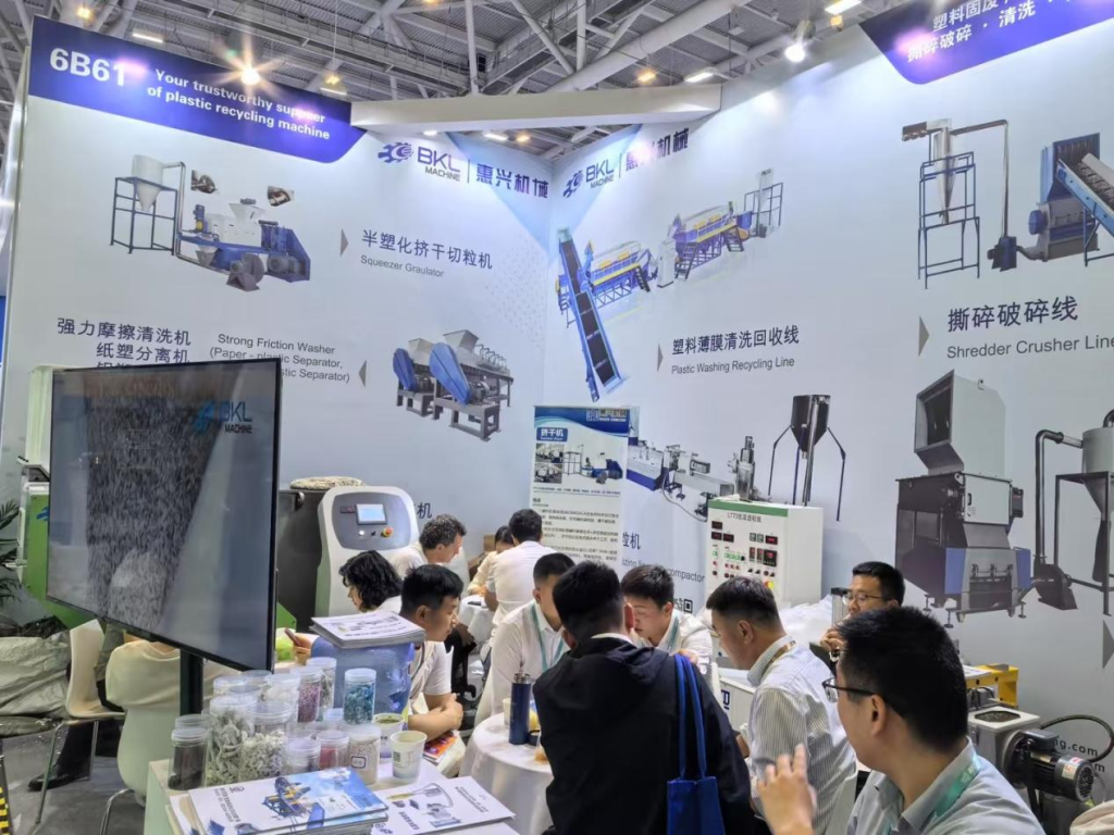 Wide view of Booth 6B61 with the equipment illustration wall, granule samples and visitors at BKL-MACHINE
