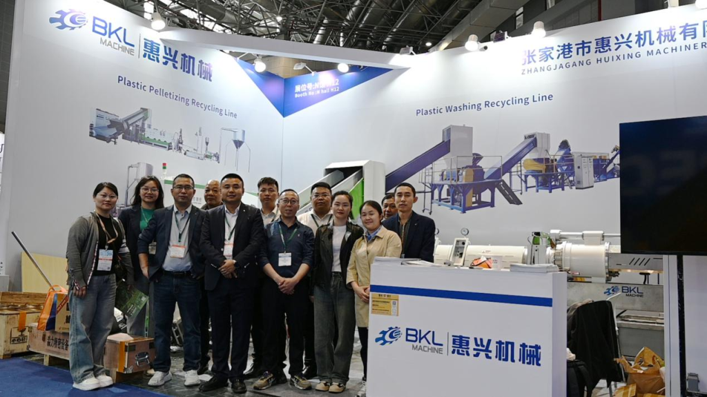 Sales and engineering team in front of the washing and pelletizing line wall graphics at the BKL-MACHINE booth