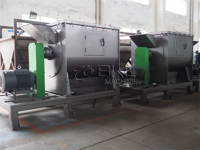 Horizontal centrifugal dewatering machine with a grey drum housing and a green drive guard, standing on a workshop floor.