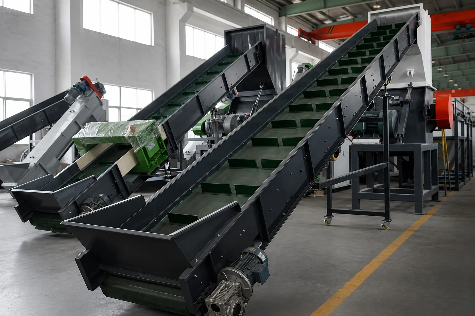 Three inclined belt conveyors with tall steel side walls and cleated belts standing on a workshop floor, the nearest driven by a geared motor at its lower end