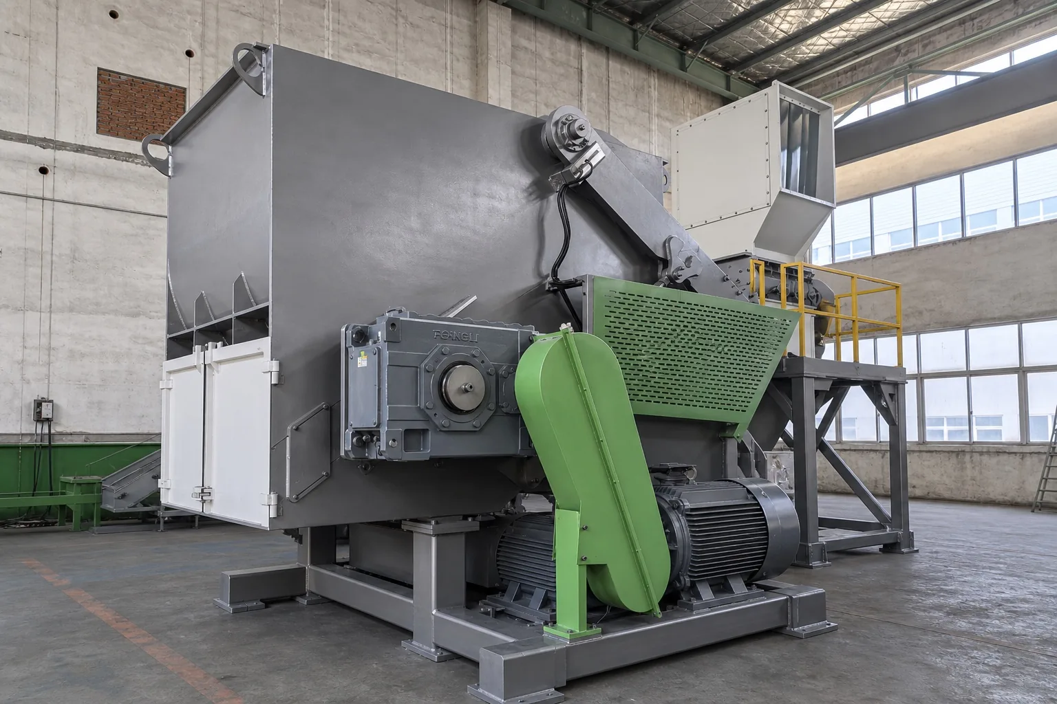 Single-shaft shredder with gearbox, green belt guard and main motor seen from the discharge side