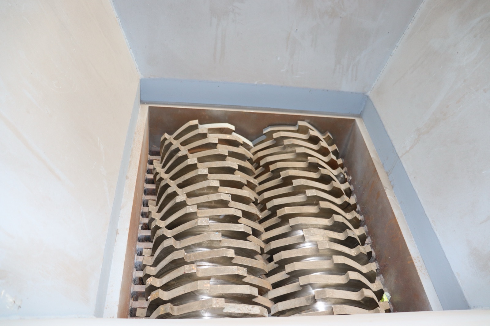 Two counter-rotating shredder rotors with interlocking hook blades viewed down through the feed hopper of a DS twin-shaft shredder