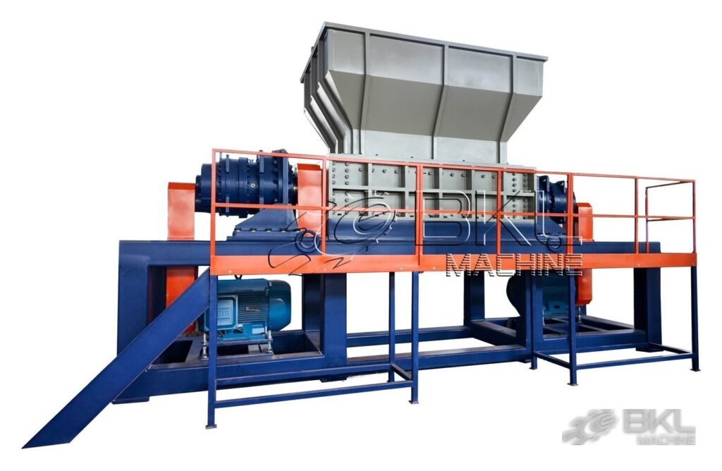 DS twin-shaft shredder with two side gearboxes, orange access platform railing and inclined discharge chute
